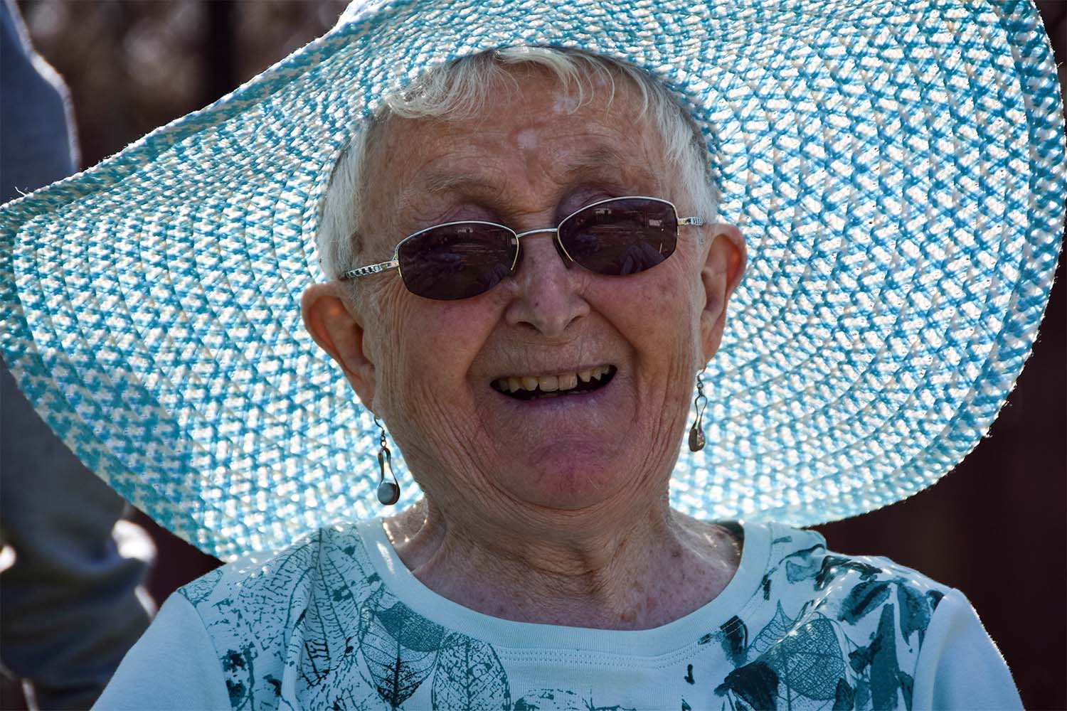 female resident smiling with a blue top and hat on in the sum