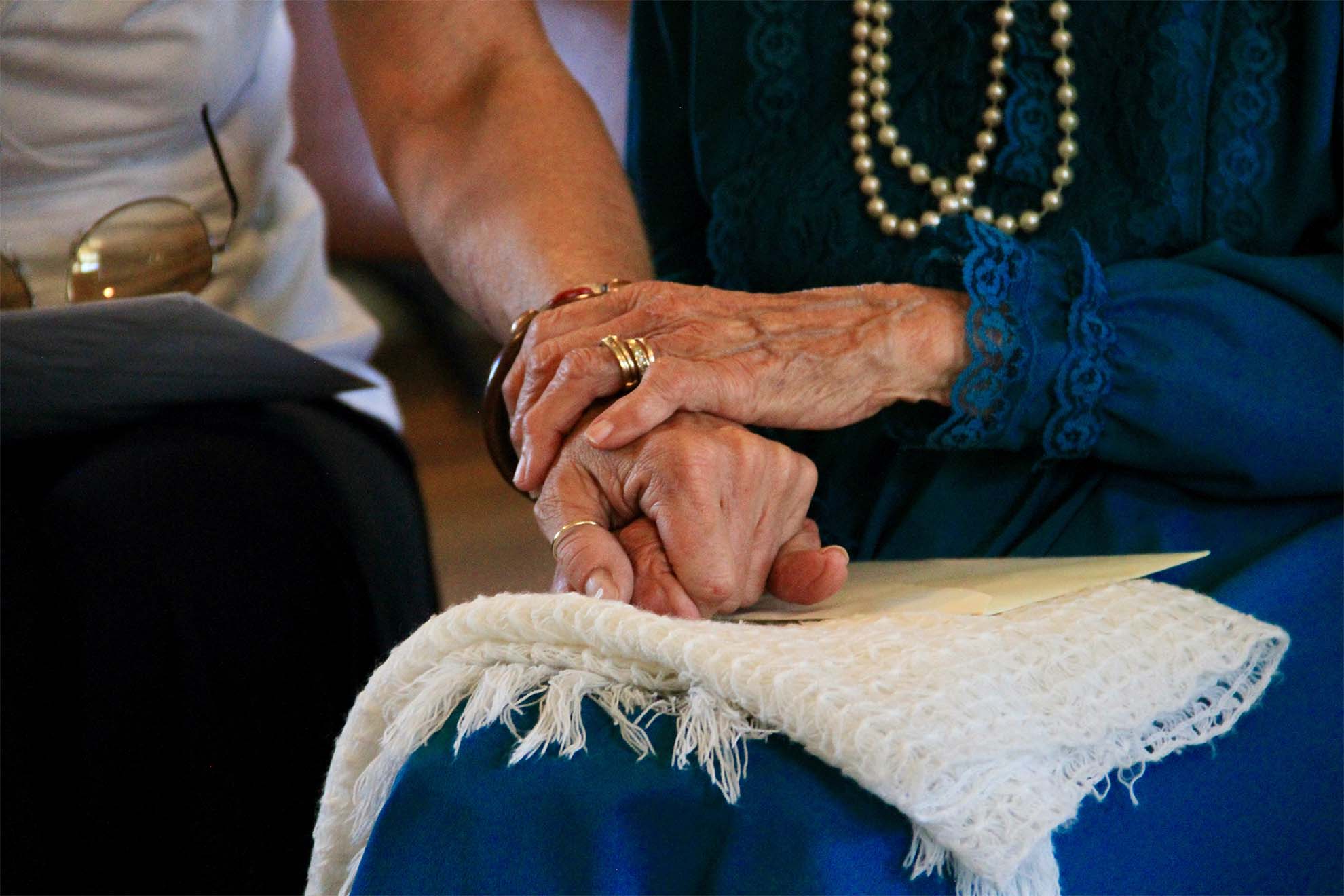 close up view of resident and carer sat down holding hands